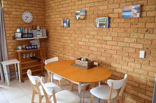 a table and chairs in a room with a brick wall at Seacrest 5 - Bring your own linen. in South West Rocks