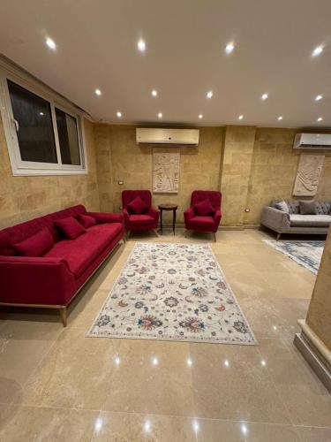a living room with red couches and a rug at Mirage pyramids view hotel in Cairo