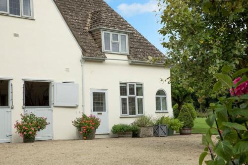 a white house with flowers in front of it at Cotswold Stable Cottage in Bibury