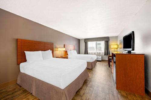 a hotel room with two beds and a flat screen tv at Best Western Inn at the Rogue in Rogue River