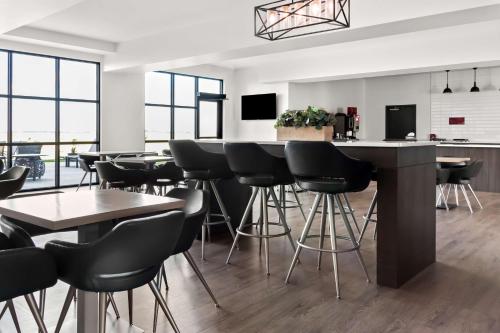 a bar with black stools in a room with windows at Best Western Plus Morden in Morden