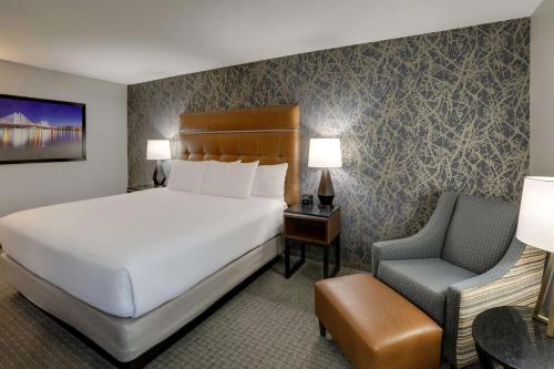 a hotel room with a bed and a chair at Drury Inn & Suites Cape Girardeau in Cape Girardeau