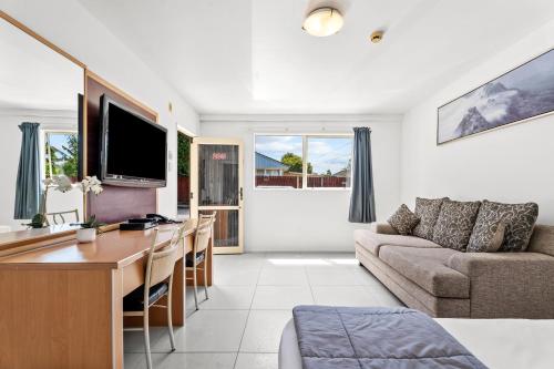 a living room with a couch and a desk at Avondale Motor Inn in Auckland
