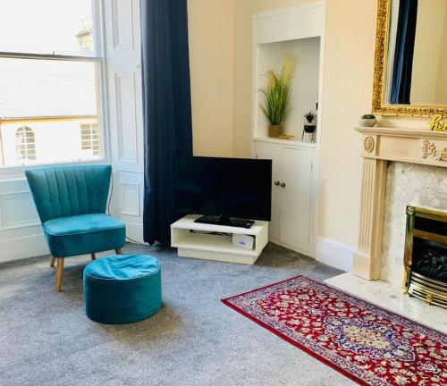 ein Wohnzimmer mit einem blauen Sessel und einem Fernseher in der Unterkunft Quiet apartment close to station & Stirling Castle in Stirling