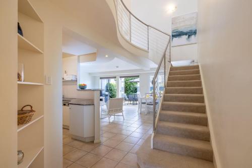 a staircase in a home with a kitchen and a dining room at Sandcastles 4 -8 Ala Moana Way in Fingal Bay