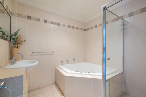 a bathroom with a tub and a sink at Sandcastles 4 -8 Ala Moana Way in Fingal Bay