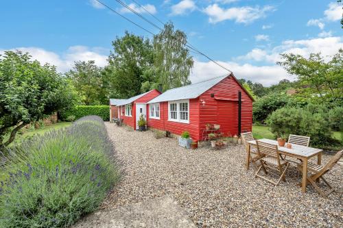 a row of red houses with a table and a bench at The Red Shed Entire home for 2 Private garden and parking 2 miles from Bury St Edmunds in Whepstead