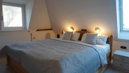 a bedroom with a large bed with two windows at Doktors Hus in Oldenswort