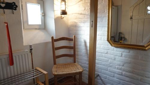 a wooden chair in a room with a mirror at Doktors Hus in Oldenswort