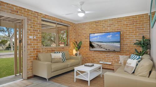 a living room with two chairs and a brick wall at Jervis Joy in Callala Beach