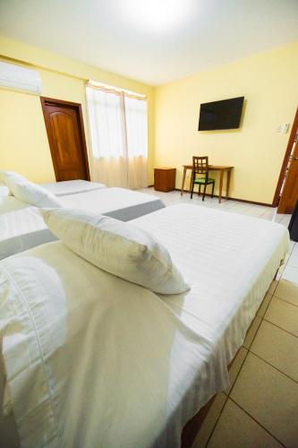 a large white bed in a room with a chair at Kovakii Hotel in Tarapoto