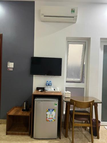 a kitchen with a table and a refrigerator and a table and chair at Khách Sạn Trung Anh 78 HAI BÀ TRƯNG BMT in Buon Ma Thuot