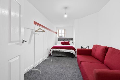 a living room with a red couch and a bed at Poets Court in West Bromwich
