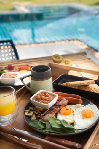 a tray of breakfast food on a table near a pool at Bungalow Khao Lak in Khao Lak