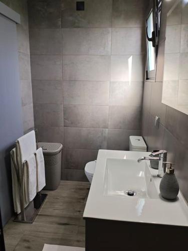a bathroom with a white sink and a toilet at Vаrаndаs dо Sоl-Vista relaxante entre mar e montanha in Ponta do Sol