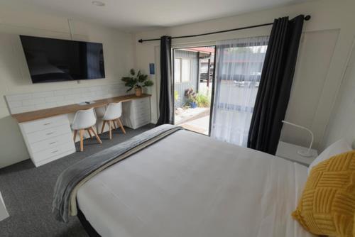 a bedroom with a large white bed and a television at Marton Motel NZ in Marton