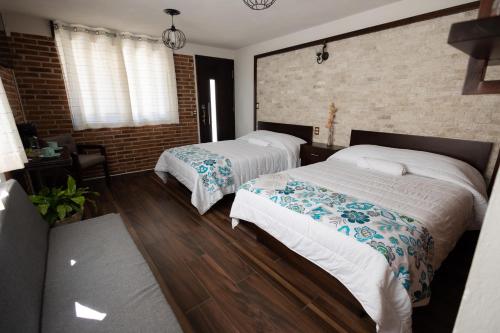 a bedroom with two beds and a brick wall at El descanso casa-hotel zacatlán. in Zacatlán