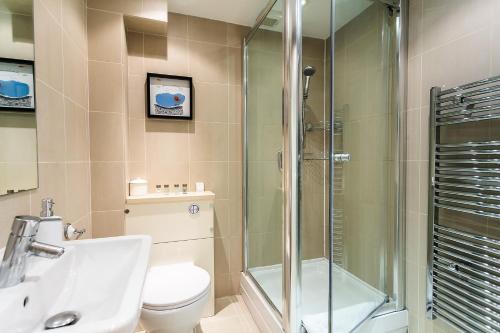 a bathroom with a shower and a toilet and a sink at Longridge Road Apartments By Viridian Apartments in London