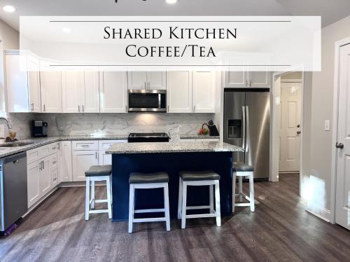 a kitchen with white cabinets and a blue island with bar stools at Rest Easy in North Carolina in Denver