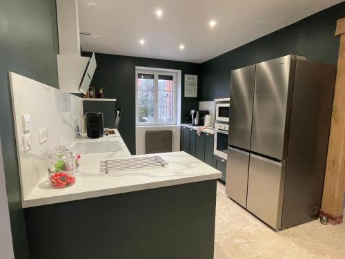 une cuisine avec un réfrigérateur en acier inoxydable et un évier dans l'établissement Gîte élégant avec SPA, réception et accessibilité PMR près de Paris - FR-1-590-442, à Lorcy