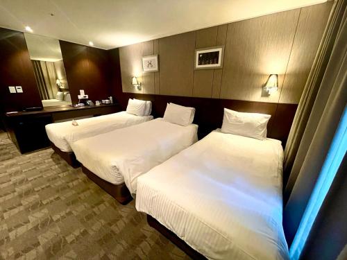 a hotel room with two beds and a bathroom at Ramada by Wyndham Jeju City Hall in Jeju