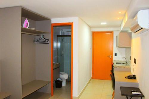 a bathroom with an orange door and a toilet at Manaíra Apart Hotel by Day by Day *1702* in João Pessoa