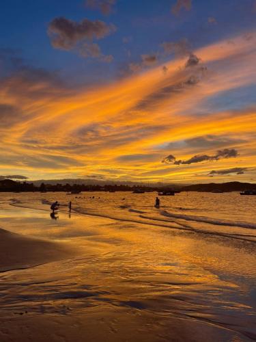 a sunset on a beach with people in the water at Floripa Jurerê, pé na areia! Apto 6 in Florianópolis