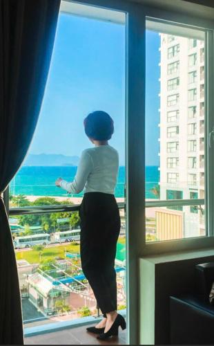a woman looking out of a window at the ocean at Sky Beach D20 Nha Trang in Nha Trang