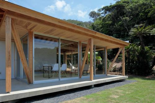 a house with glass walls and a wooden roof at SHINMINKA Villa UTTABARU in Amami