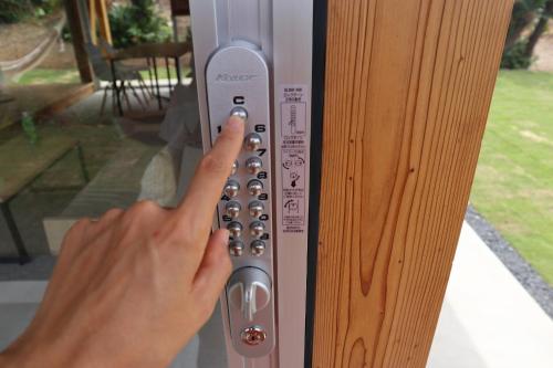 a person pressing a door button on a wooden door at SHINMINKA Villa UTTABARU in Amami