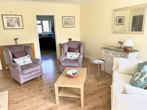 a living room with two chairs and a table at Daisy Cottage in Lymington