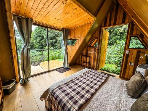 a bedroom with a bed and a large window at Tityra Lodge in Monteverde Costa Rica