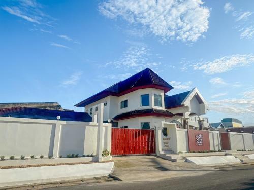 a white house with a blue roof and a red gate at The Star Pool Villa Hatyai in Hat Yai