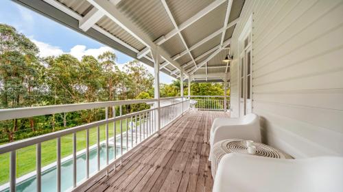 a balcony with white furniture on a white house at Ananda - Magnificent Byron Hinterland Retreat in Myocum
