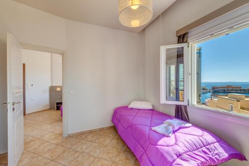 a purple bed in a room with a window at Ethrion in Ermoupoli