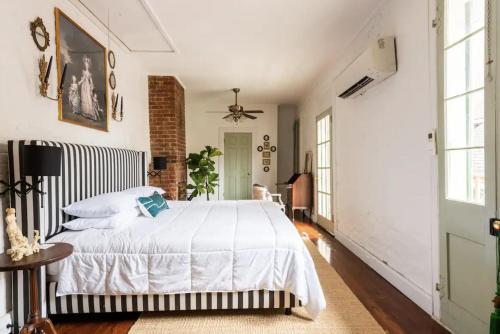 a bedroom with a white bed and a brick wall at Chic Cottage near the Lower French Quarter in New Orleans