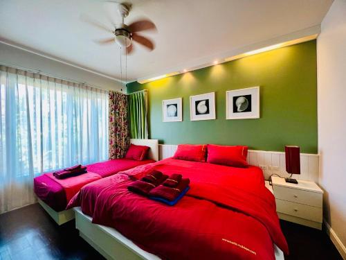 a bedroom with a red bed with a green wall at Baan Sandao by Nanni in Hua Hin