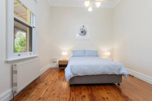 a white bedroom with a bed and a window at Bellisle - 1880's period home in Central Albury in Albury