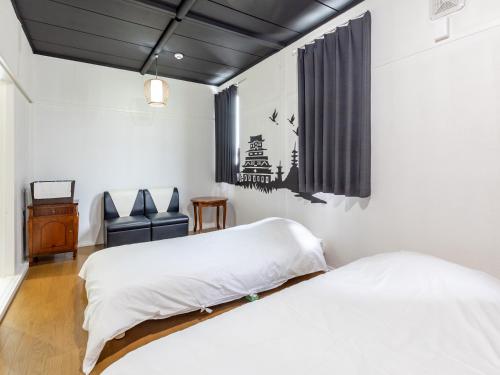 a bedroom with two beds and a chair at Tabist Hotel Kippaku in Takamatsu