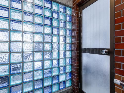 a glass block wall with a door in a room at Tabist Hotel Kippaku in Takamatsu