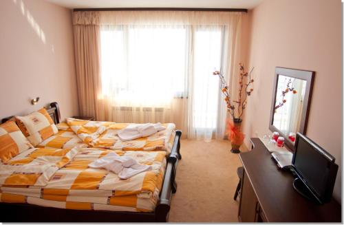 a bedroom with a bed and a desk and a window at Family hotel Iskar in Govedartsi