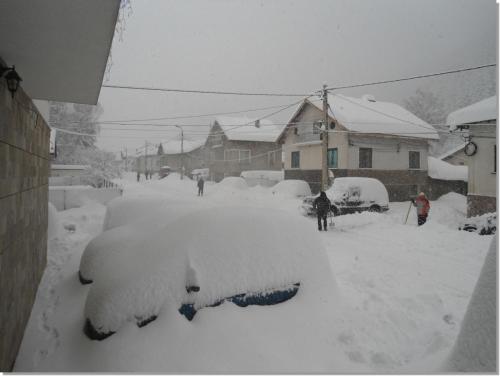 a car covered in snow in a yard at Family hotel Iskar in Govedartsi
