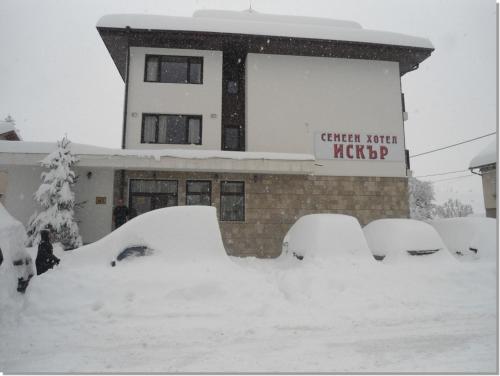 a building covered in snow in front of a building at Family hotel Iskar in Govedartsi