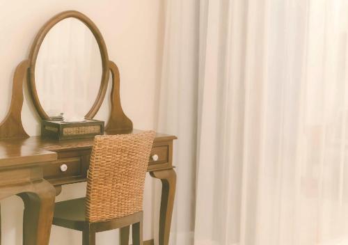 a dressing table with a mirror and a chair next to a curtain at Yesterday Hotel in Chiang Mai