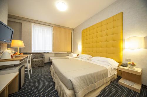 a hotel room with a large bed and a desk at Hotel Bisanzio in Ravenna