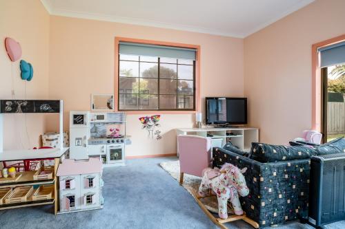 a living room with a couch and a tv at Family Beach House Near Barwon River & Beaches in Barwon Heads