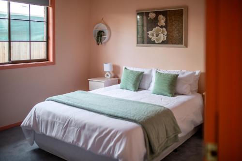 a bedroom with a large bed with green and white pillows at Family Beach House Near Barwon River & Beaches in Barwon Heads