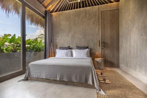 a bedroom with a bed and a large window at The Konkret Lombok in Kuta Lombok