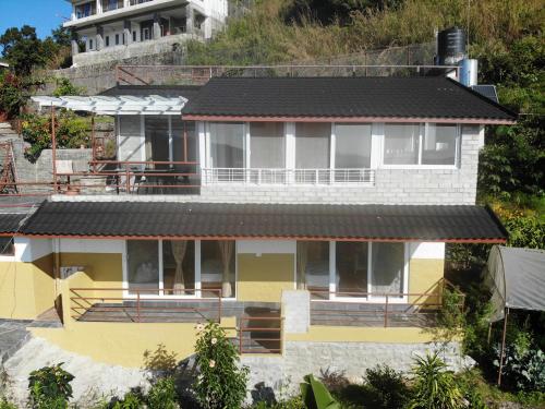 a yellow and white house with a black roof at The North Face Inn's Homestay in Pokhara