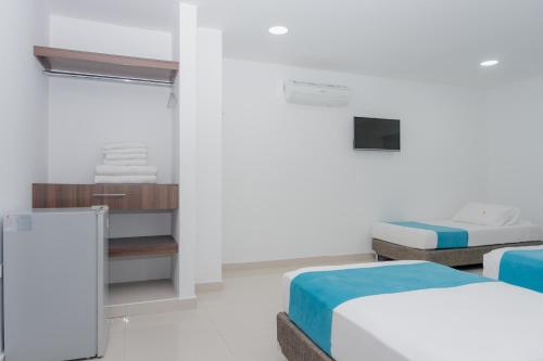 a white room with two beds and a mirror at Hotel Aguamarina in Santa Marta